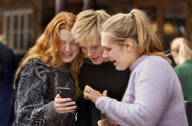 en gruppe unge ser på en mobiltelefon
